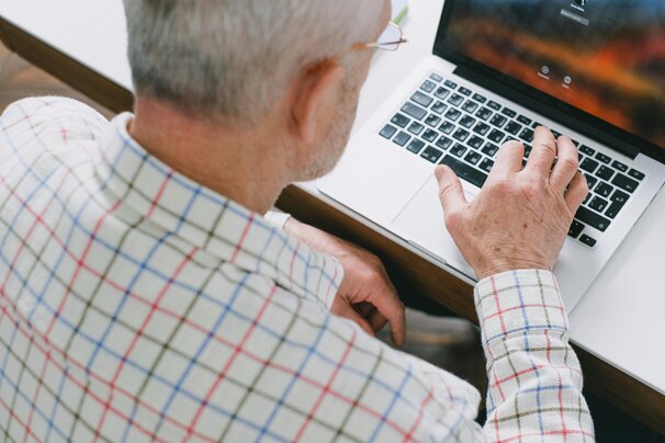 Une personne aidant un sénior à utiliser une tablette numérique